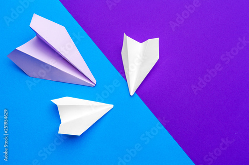 white paper airplane on a blue and purple paper background