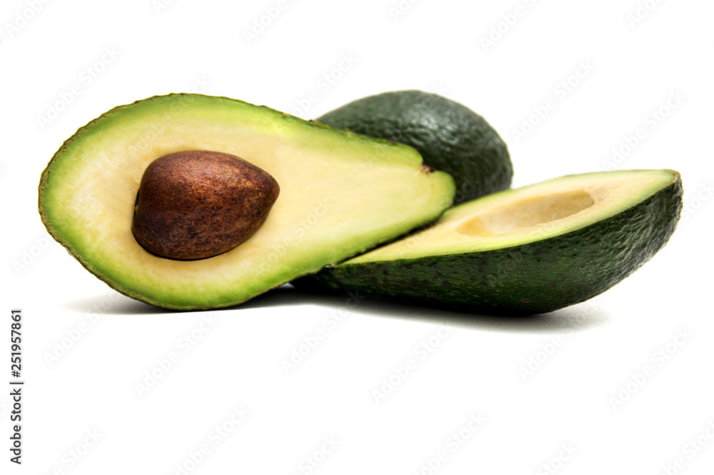 green avocado cut in half lying on a white background
