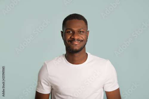 adult african man in a white t-shirt with a cheerful face on a blue background