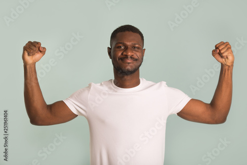 handsome african man in white t-shirt showing his strength