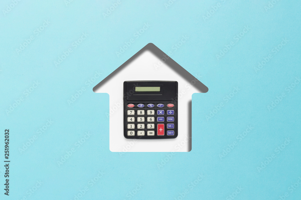 Blue cardboard cut in the shape of a house and calculator. Concept of buying a home, mortgage, credit for home, planning. Flat lay, top view