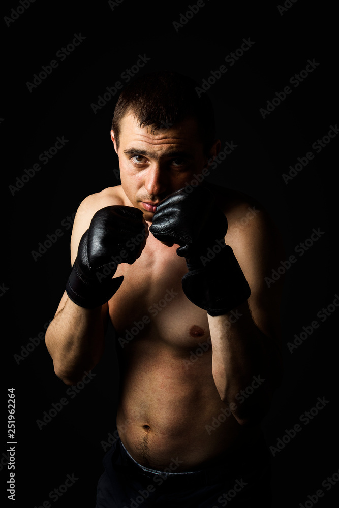 A man in gloves for fighting without rules MMA on a black background. Workout concept, combat training A man in gloves for fighting without rules MMA on a black background. Workout concept, combat training