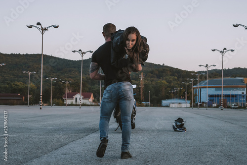 Girl and guy bikers love each other. Fooling around and having fun. Love. Motorcycles, helmets, road, leather, sunset. photo