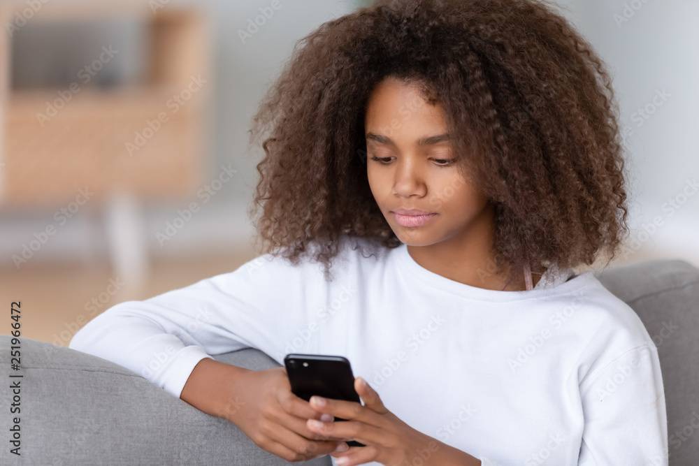 Close up african teenager girl sitting on couch using smartphone Close up african teenager girl sitting on couch using smartphone