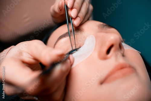 Eyelash extension procedure close up. Beautiful woman with long eyelashes in a beauty salon. Lifestyle. Beauty and fashion. Personal care.