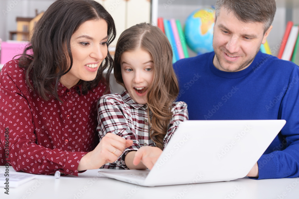Portrait of parents and daughter using laptop in room Portrait of parents and daughter using laptop in room