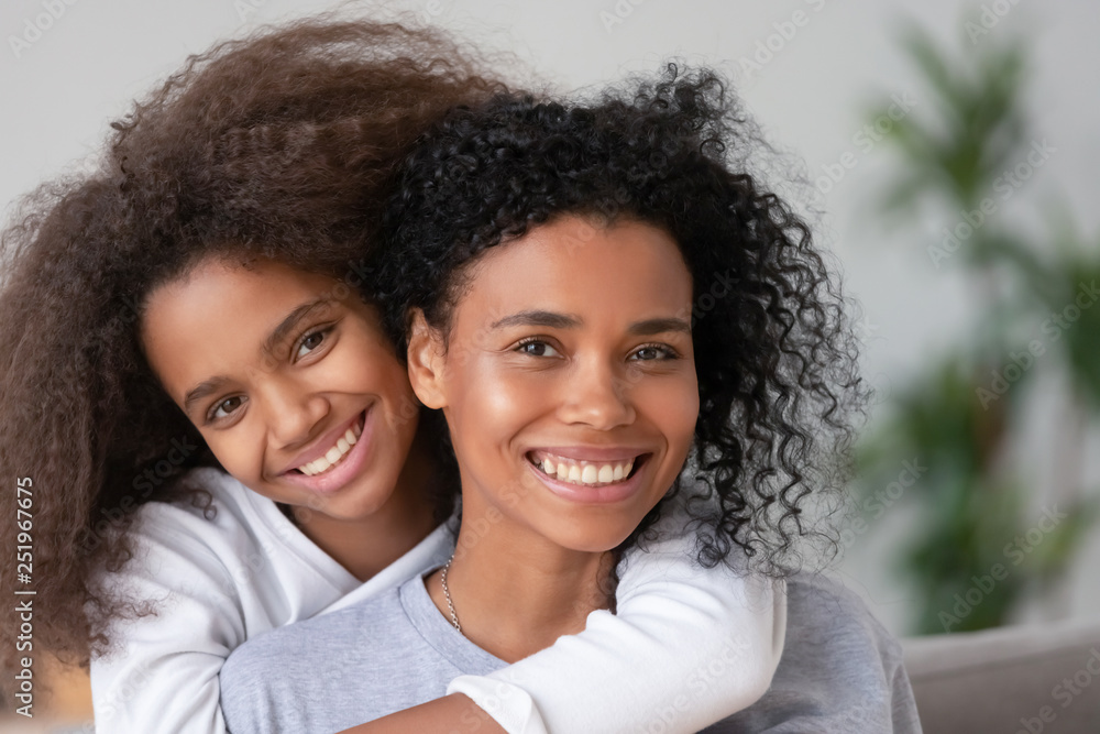 African happy mother and daughter cuddling looking at camera African happy mother and daughter cuddling looking at camera