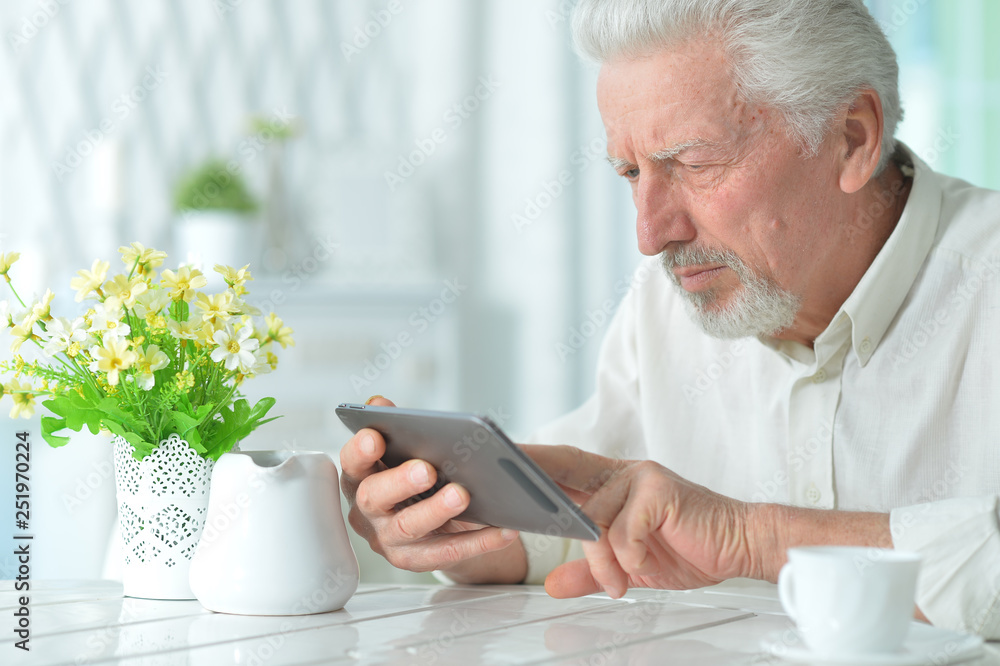 Portrait of thoughtful senior man using tablet