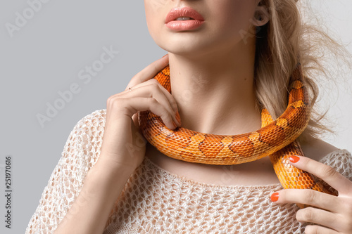 Fotobehang Young, beautiful, woman with snake around her neck on grey background