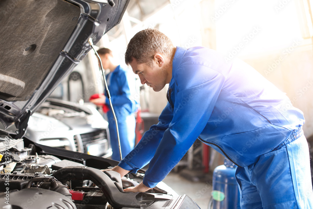 Obraz premium Mężczyzna mechanik naprawy samochodu w centrum obsługi
