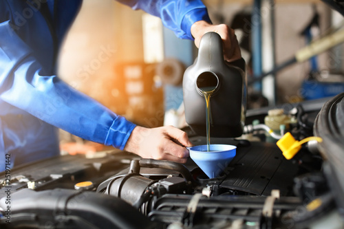 Male mechanic refilling car oil in service center photo