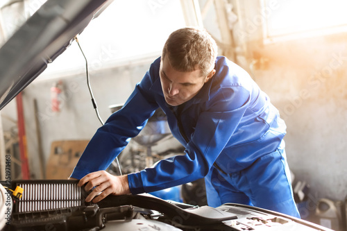 Male mechanic examining car...