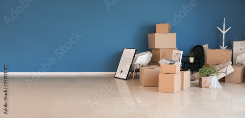 Carton boxes and interior items prepared for moving into new house near color wall photo