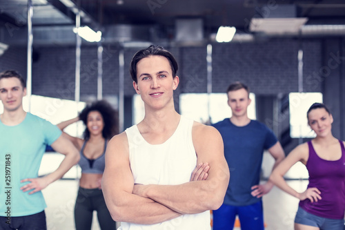 Sporty man with group of athletes in gym