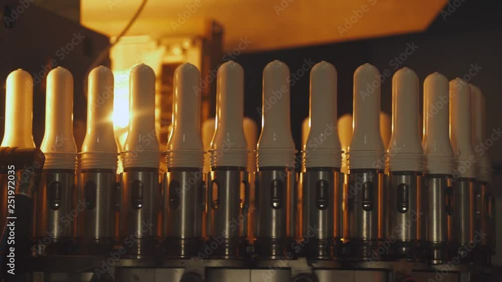 Production of drinking milk, view of white flasks, blanks for plastic bottles in conveyor, warm light. Production of drinking milk, view of white flasks, blanks for plastic bottles in conveyor, warm light.