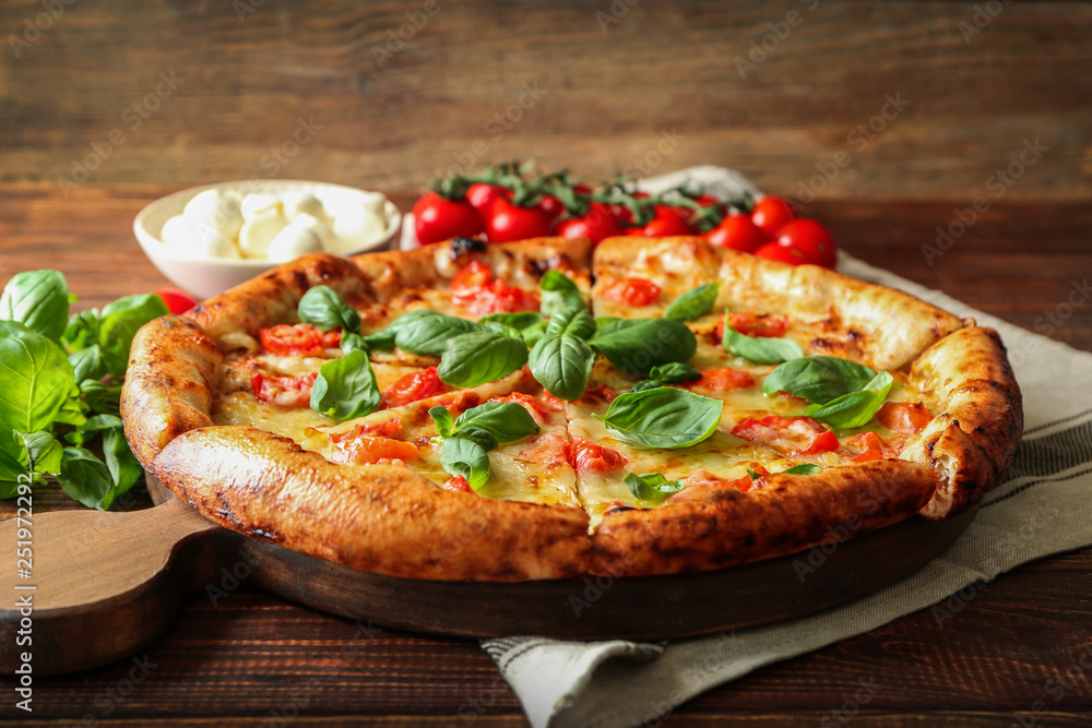 Board with delicious pizza Margherita on wooden table