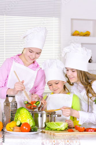Portrait of happy cute girls cooking vegetable dish