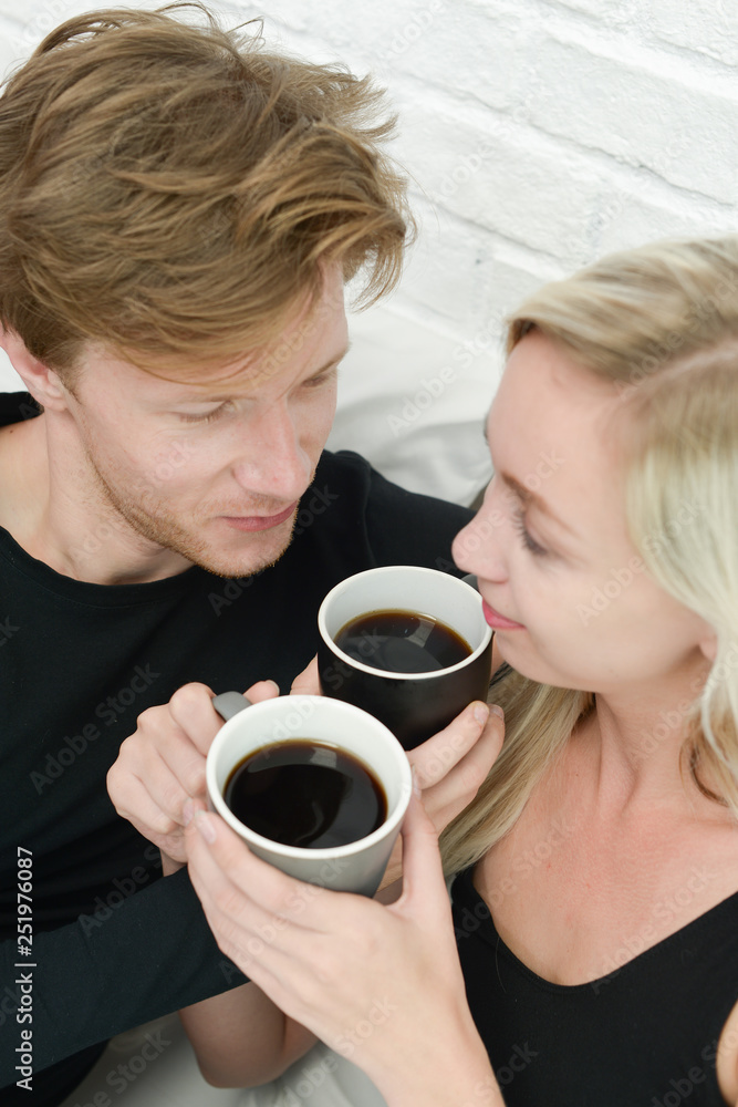Beautiful young smiling woman sitting on bed with a cup of coffee in the morning at bedroom. Beautiful young smiling woman sitting on bed with a cup of coffee in the morning at bedroom.
