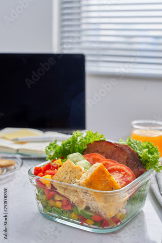 Businesswoman eating organic vegan meals from take away lunch box at  working table with laptop
