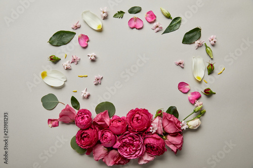 top view of round floral frame made of pink roses and petals with copy space isolated on grey