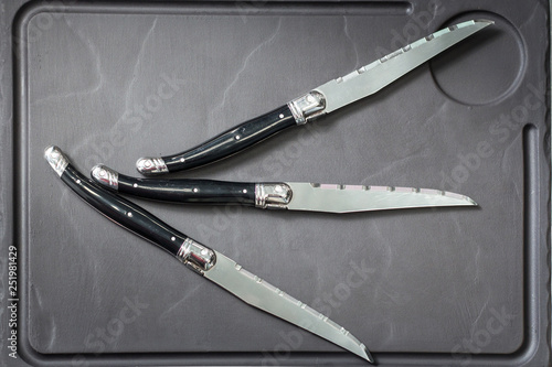 Three knifes on a gray plate as a concept