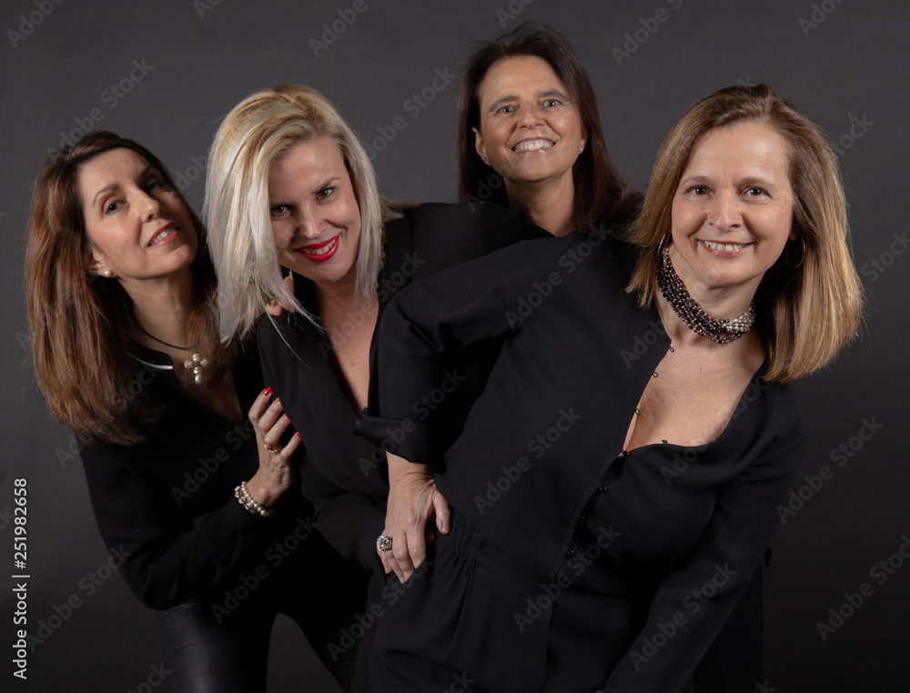 Four friends posing in a studio with a black background Four friends posing in a studio with a black background