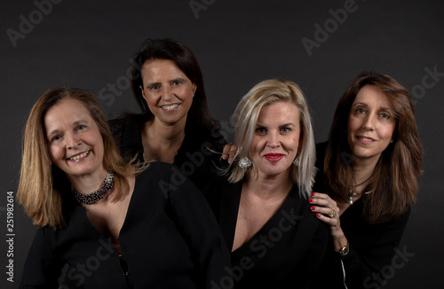 Four friends posing in a studio with a black background