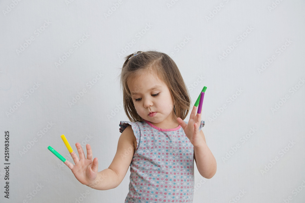 little girl playing with felt tip pens. baby girl painting and playing. colorful stuff felt pen caps on fingers of kid little girl playing with felt tip pens. baby girl painting and playing. colorful stuff felt pen caps on fingers of kid