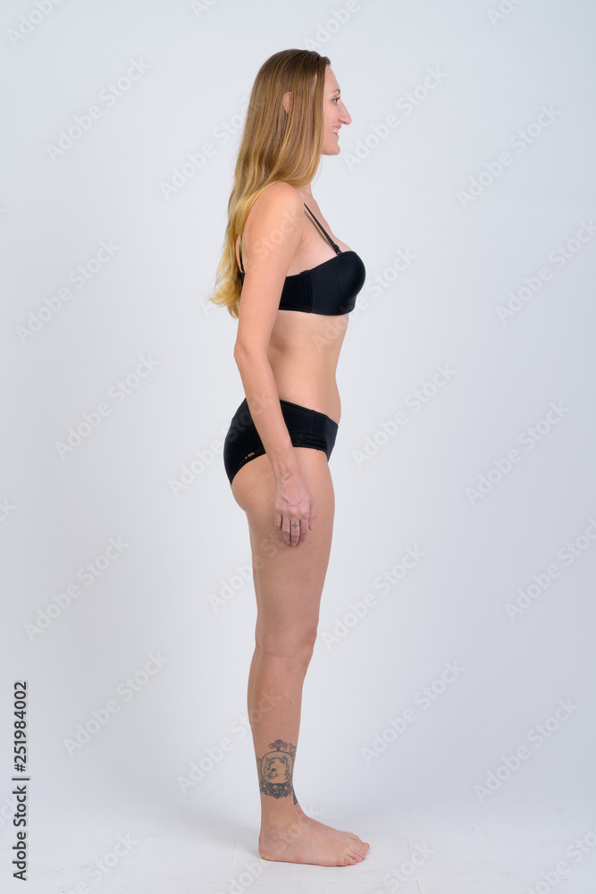Full body shot profile view of happy blonde woman in bikini smiling
