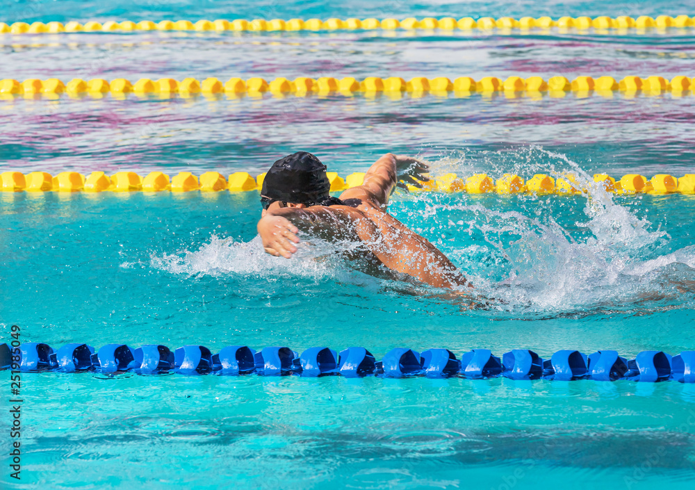 swimmer is swimming in butterfly stroke during competition in to the pool
