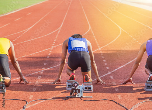 Rear Back view male athletes ready preparing for race on starting blocks in running track at stadium photo