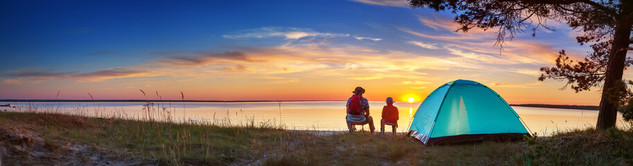 Family resting with tent in nature at sunset