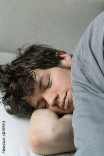 Cute handsome young man sleeping on bed.