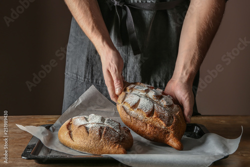 Man with freshly baked bread on table, closeup