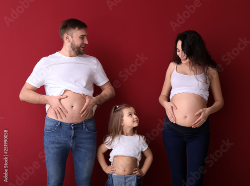 Happy family expecting baby on color background photo