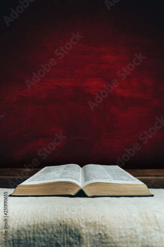 Open Holy Bible on a old  table. Beautiful dark red wooden background. Religion concept. photo