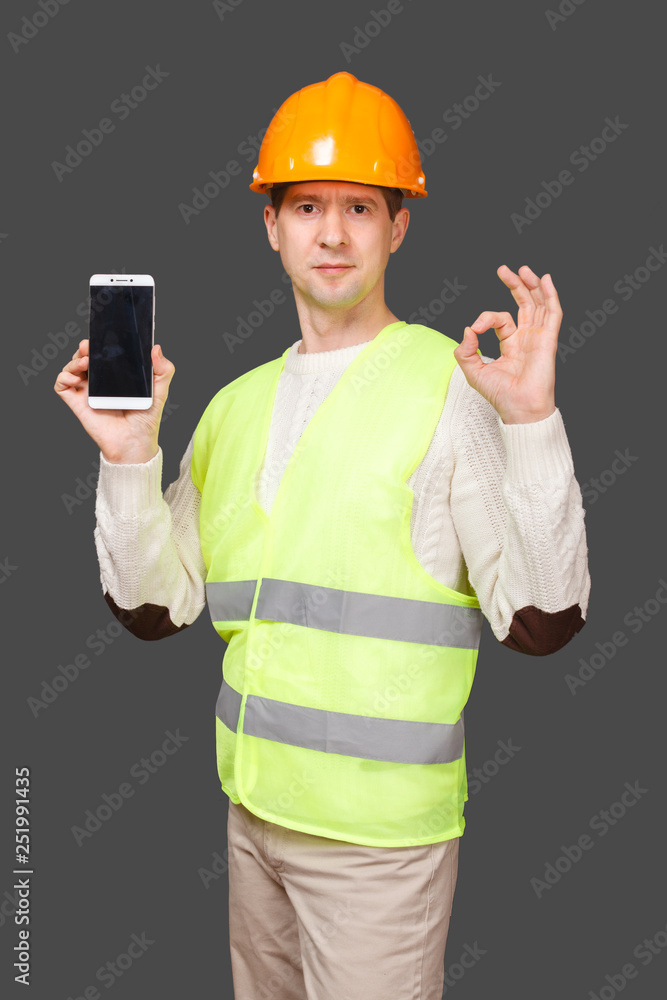 the man in a helmet with phone, shows gesture OK, everything is good