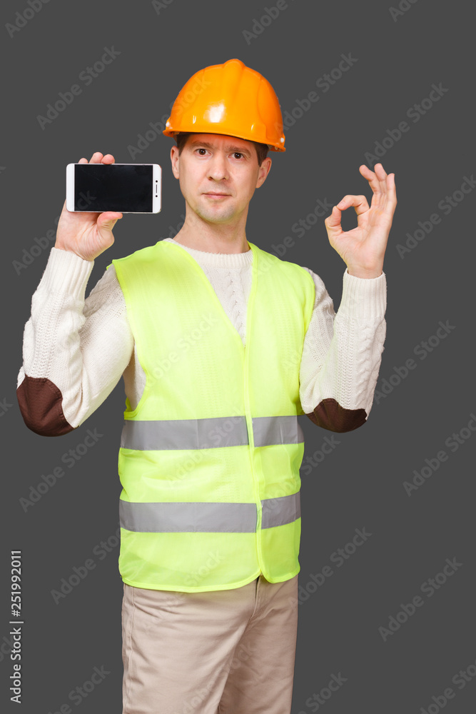 the man in a helmet with phone, shows gesture OK, everything is good the man in a helmet with phone, shows gesture OK, everything is good