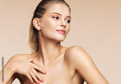 Smiling girl with flawless skin on beige background. Youth and skin care concept