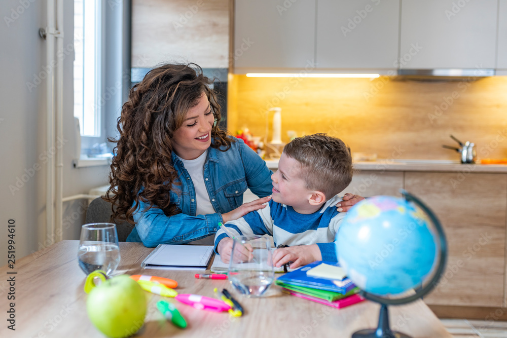 Fototapeta premium Cute boy with mother doing homework at home.