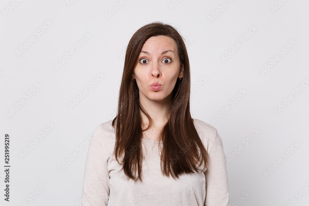 Portrait of pretty funny cute young woman in light clothes looking camera and blowing lips isolated on white wall background in studio. People sincere emotions, lifestyle concept. Mock up copy space. Portrait of pretty funny cute young woman in light clothes looking camera and blowing lips isolated on white wall background in studio. People sincere emotions, lifestyle concept. Mock up copy space.