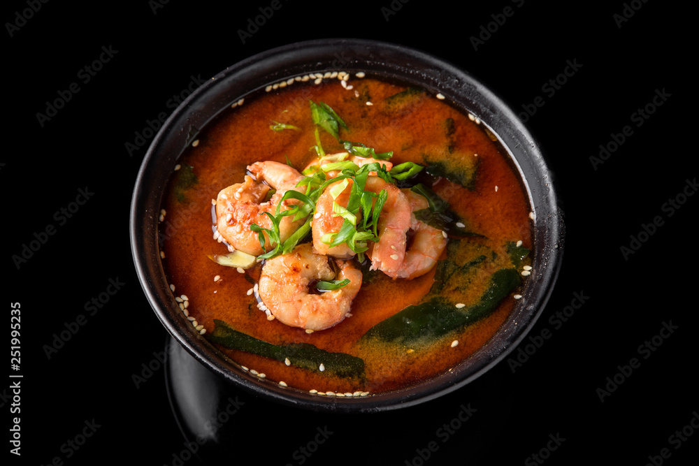 Hot miso soup with shrimp, seaweed, mushrooms, herbs in bowl on black background. Japanese food. Hot miso soup with shrimp, seaweed, mushrooms, herbs in bowl on black background. Japanese food.