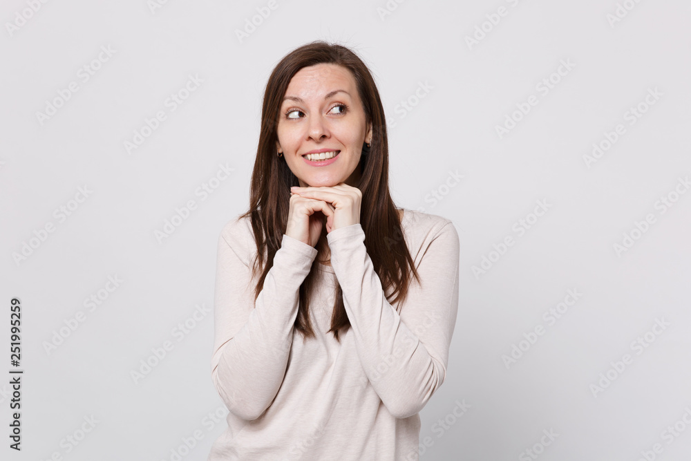 Portrait of smiling young woman in light clothes looking aside and put hand prop up on chin isolated on white wall background in studio. People sincere emotions, lifestyle concept. Mock up copy space. Portrait of smiling young woman in light clothes looking aside and put hand prop up on chin isolated on white wall background in studio. People sincere emotions, lifestyle concept. Mock up copy space.