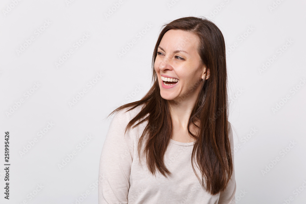 Portrait of laughing joyful attractive young woman in light clothes standing, looking aside isolated on white wall background in studio. People sincere emotions lifestyle concept. Mock up copy space. Portrait of laughing joyful attractive young woman in light clothes standing, looking aside isolated on white wall background in studio. People sincere emotions lifestyle concept. Mock up copy space.