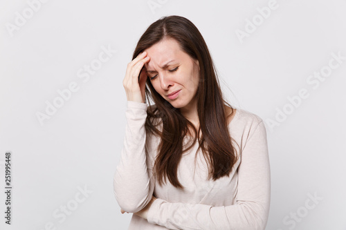 Tired displeased exhausted young woman in light clothes keeping eyes closed putting hands on head isolated on white background in studio. People sincere emotions lifestyle concept. Mock up copy space.
