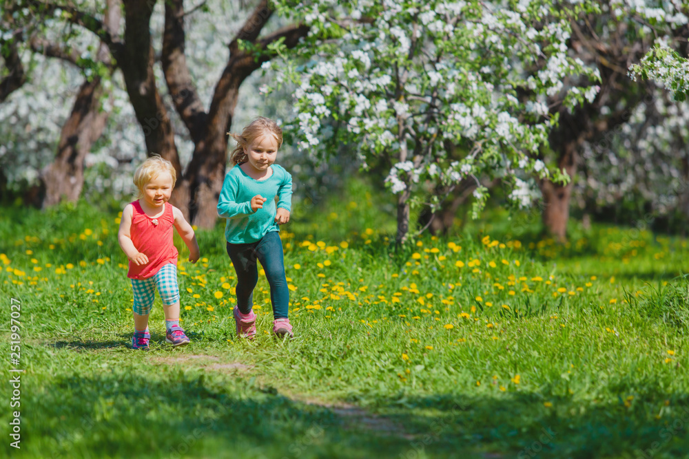 happy girls play run in spring nature, apple blossom, seasonal activities happy girls play run in spring nature, apple blossom, seasonal activities