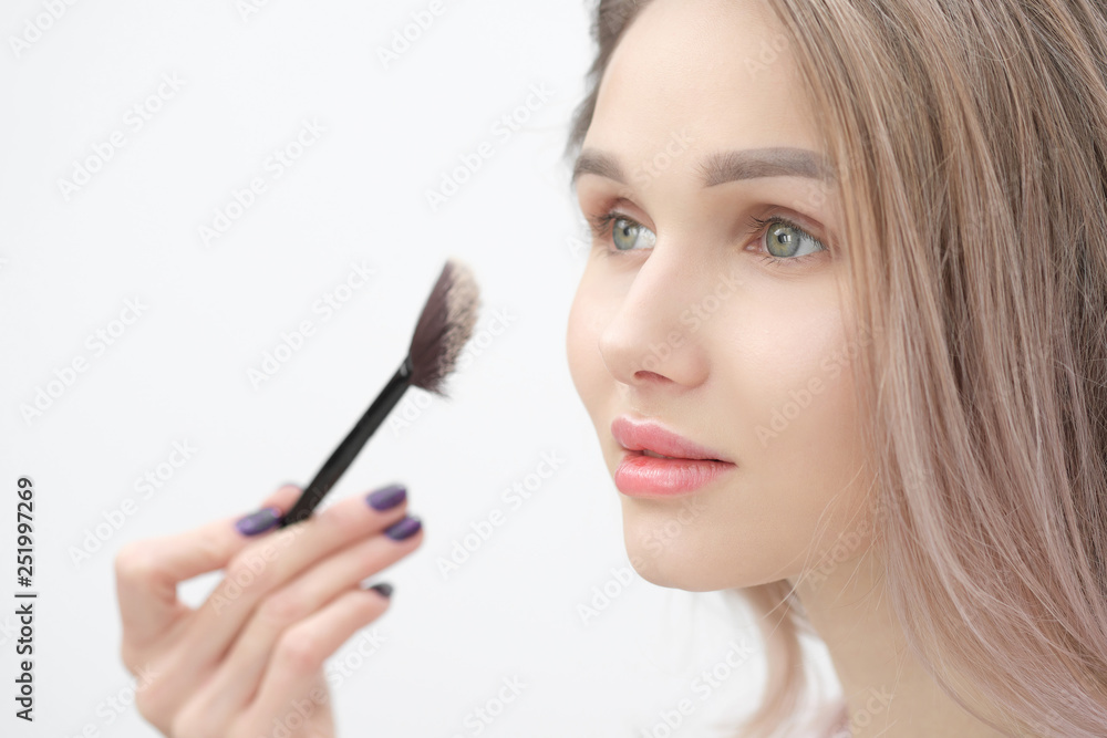 Make-up artist makes makeup beautiful blonde girl on a white background. Close-up hands with brush and face. Make-up artist makes makeup beautiful blonde girl on a white background. Close-up hands with brush and face.
