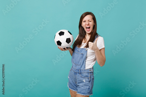 Blinking woman football fan cheer up support favorite team with soccer ball showing thumb up isolated on blue turquoise background. People emotions, sport family leisure concept. Mock up copy space. © ViDi Studio