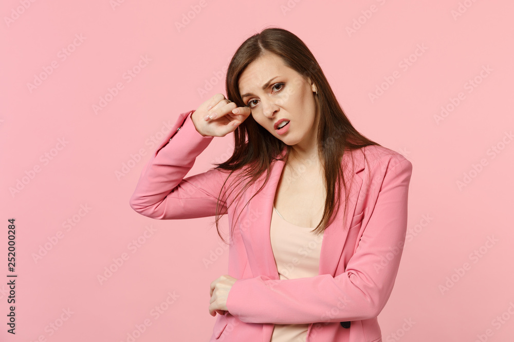 Portrait of exhausted crying young woman wearing jacket looking camera, wiping tears isolated on pastel pink wall background in studio. People sincere emotions, lifestyle concept. Mock up copy space. Portrait of exhausted crying young woman wearing jacket looking camera, wiping tears isolated on pastel pink wall background in studio. People sincere emotions, lifestyle concept. Mock up copy space.