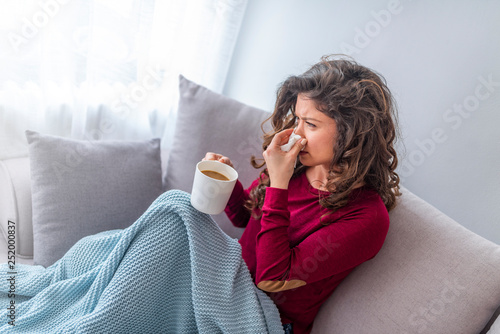 Young girl sick in bed with temperature drinks hot